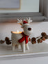 Decorative reindeer candle holder with a lit candle on a surface.