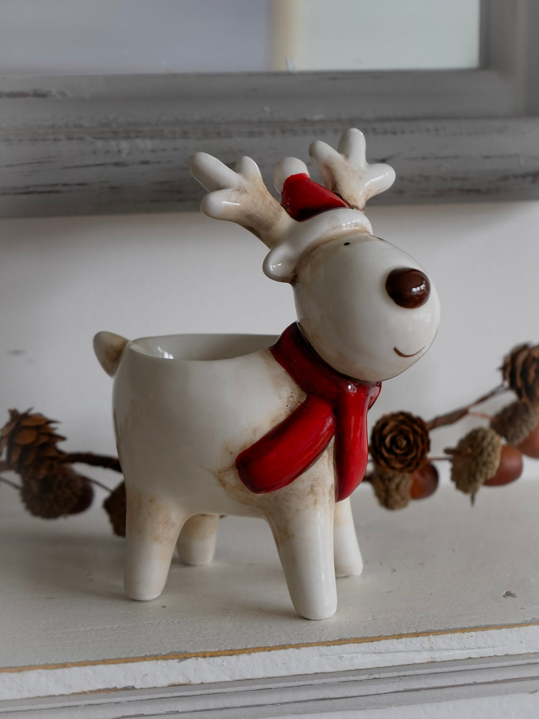 Decorative reindeer figurine with a red scarf on a white surface.