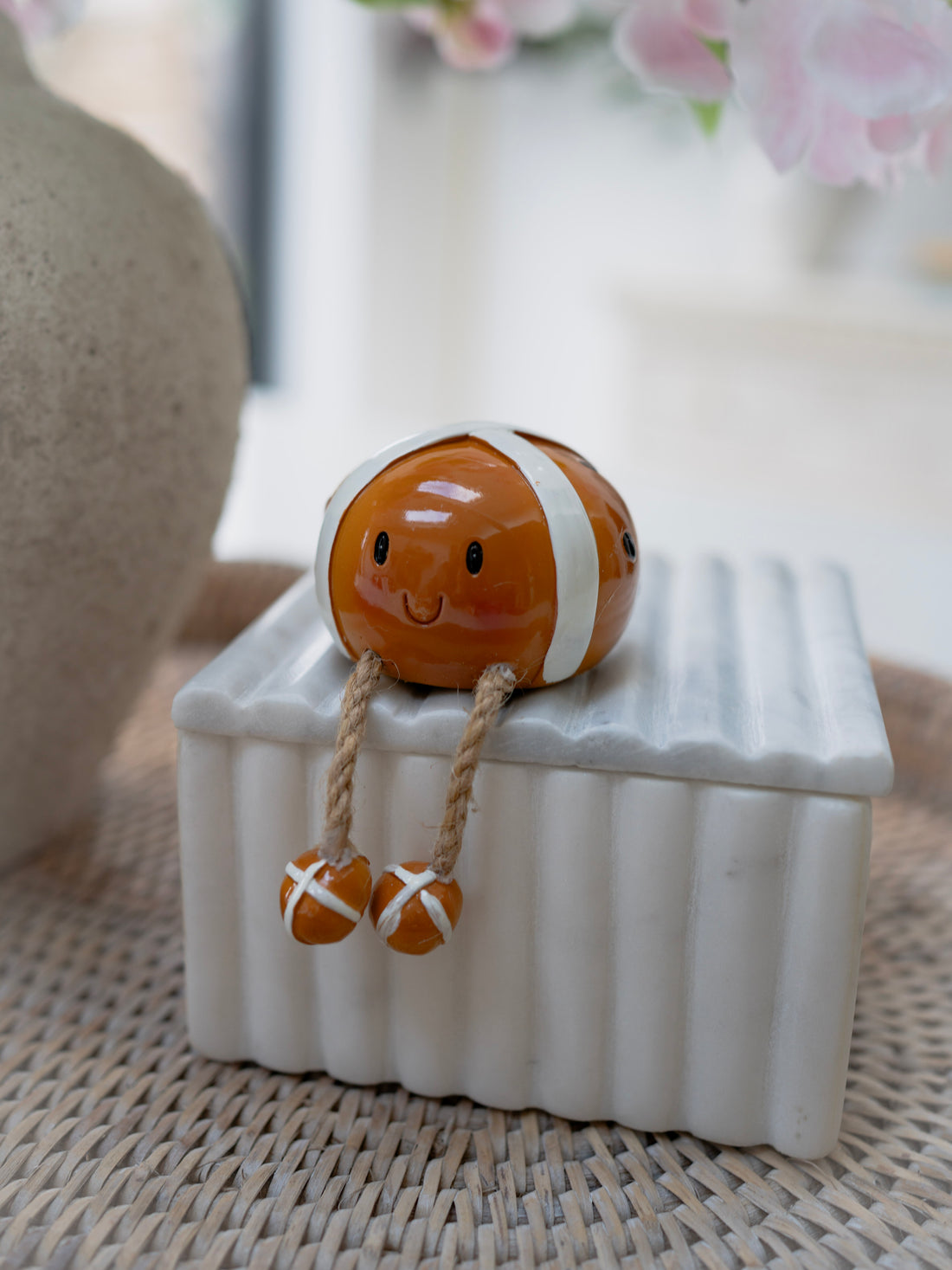 Small resin hot cross bun figurine on a white base with a blurred floral background