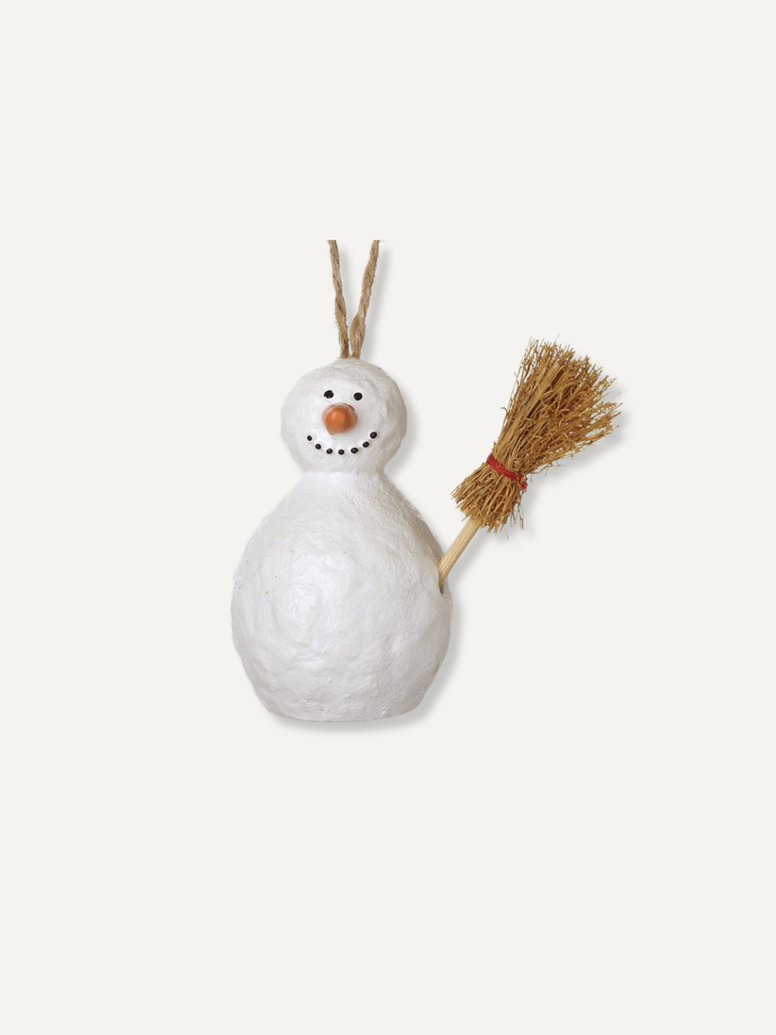 A small white snowman ornament with a textured paper-like finish, a twig nose, black dot eyes and mouth, and a straw-colored broom on its right side. The ornament hangs from two thin twigs against a plain off-white background.