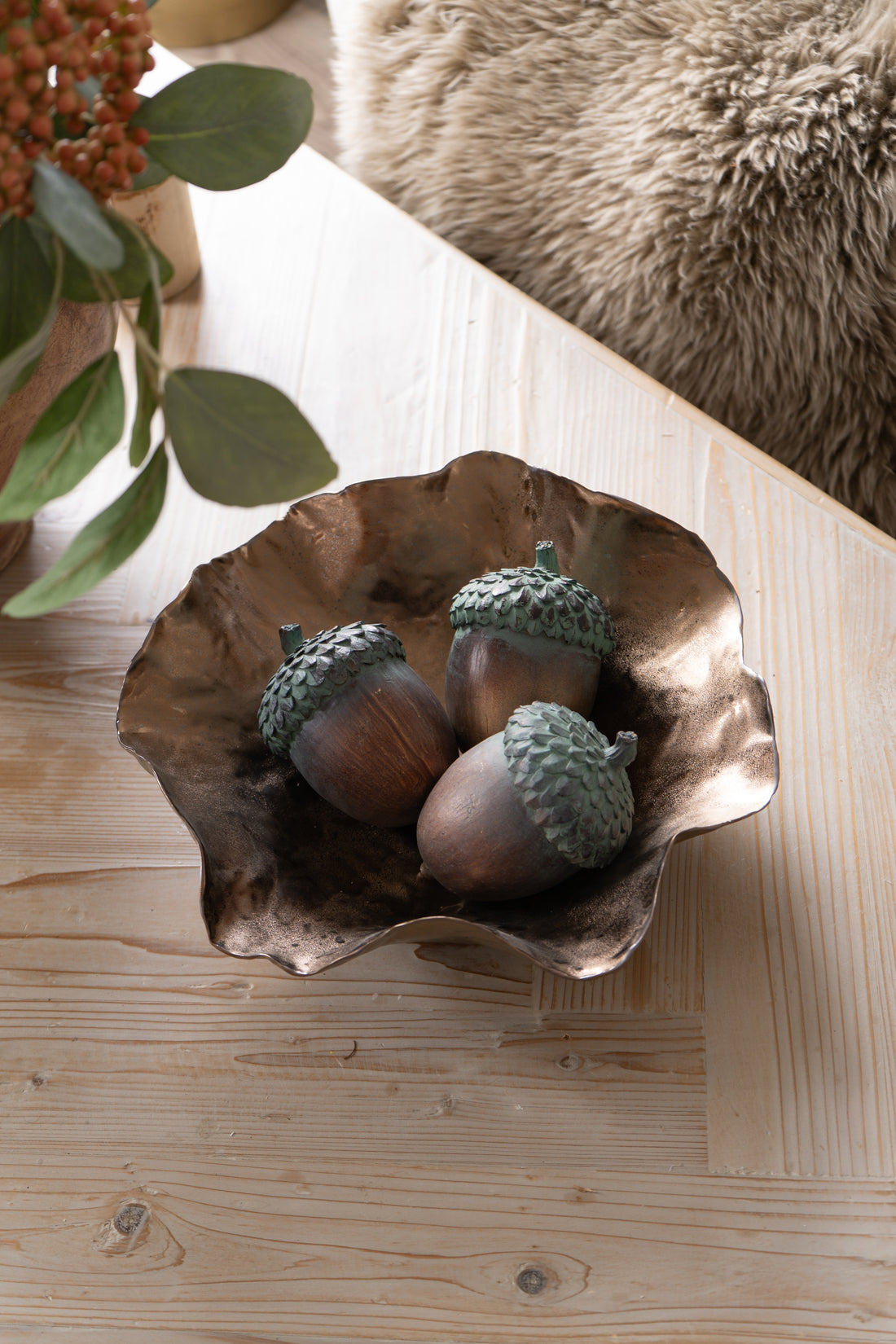 Decorative bronze bowl with acorns on a wooden surface