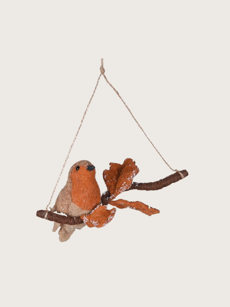 Decorative bird on a branch hanging from a string against a light background