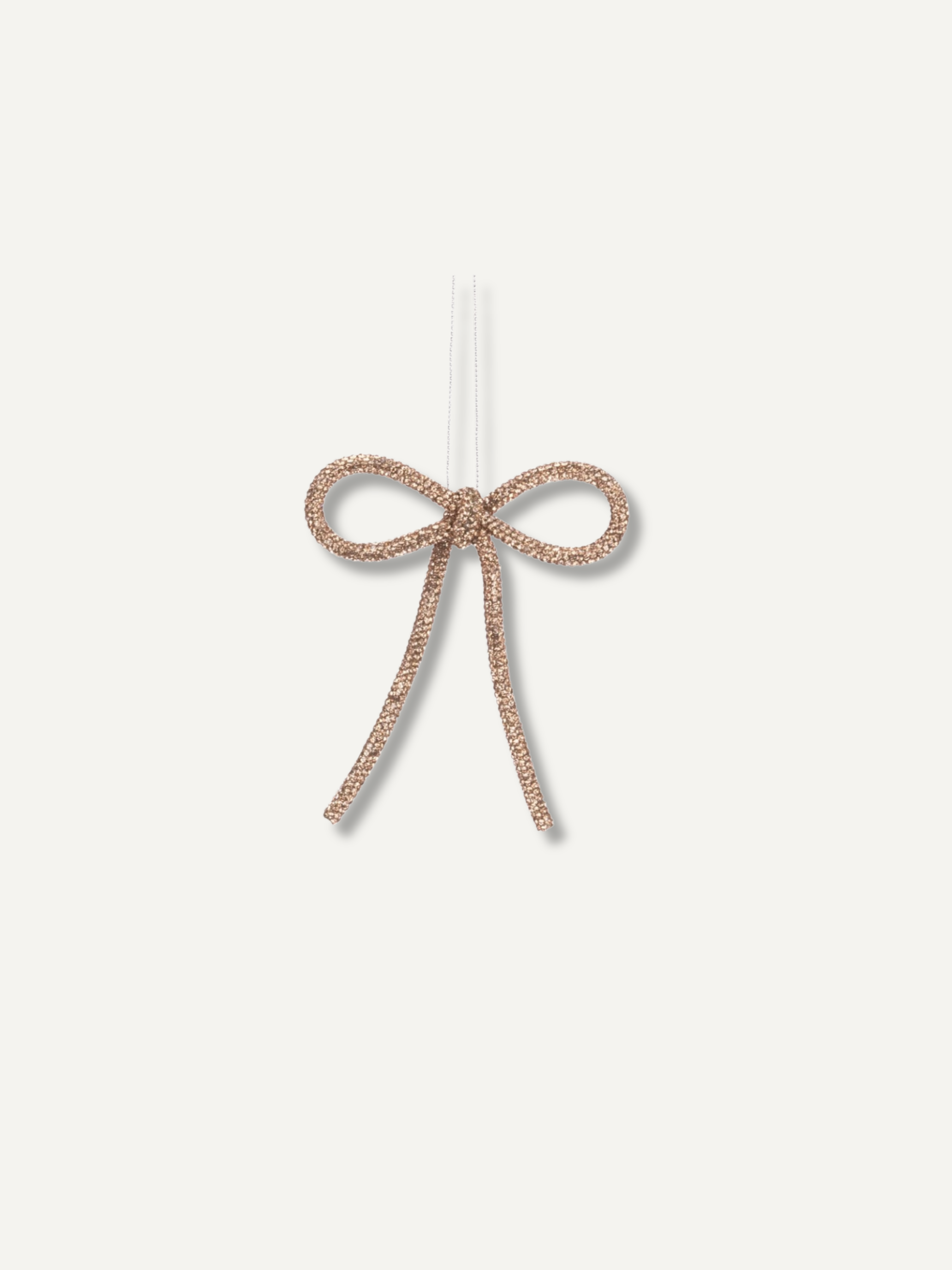A small beaded bow ornament in a rose gold tone, suspended by a clear string against a plain off-white background.