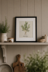 Framed rosemary botanical print on a shelf with decorative items against a panelled wall.