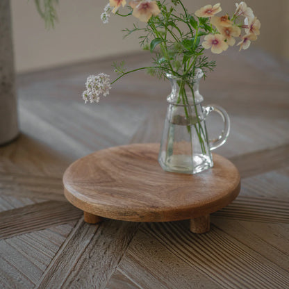 Clear glass vase with flowers on a wooden stand on a wooden surface