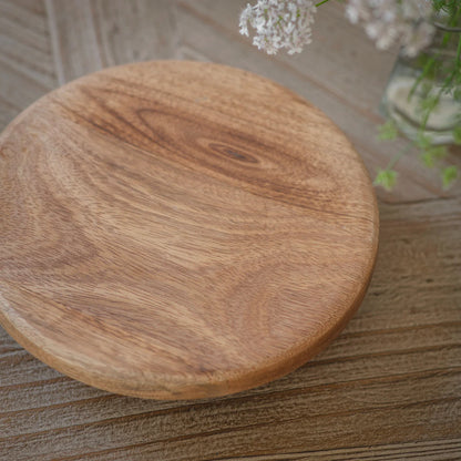 Round wooden cutting board on a wooden surface with a blurred background