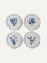 Four round white-framed wall art prints arranged in a 2x2 grid, each featuring a blue coral or sea fan illustration on a white background, set against a light beige wall.
