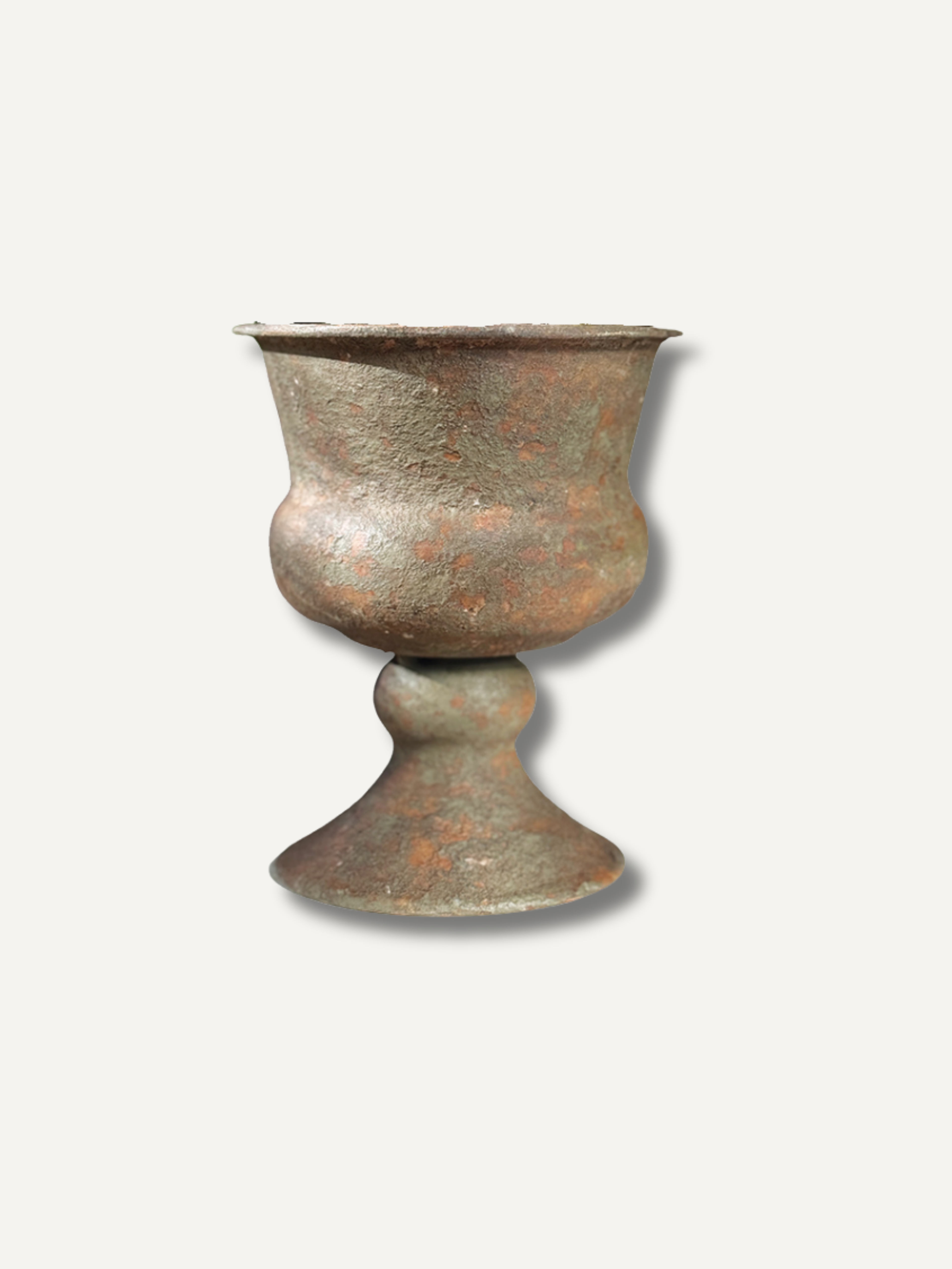 An antique-style bronze goblet or cup with a textured, weathered surface showing brown and green patina, set against a plain off-white background.