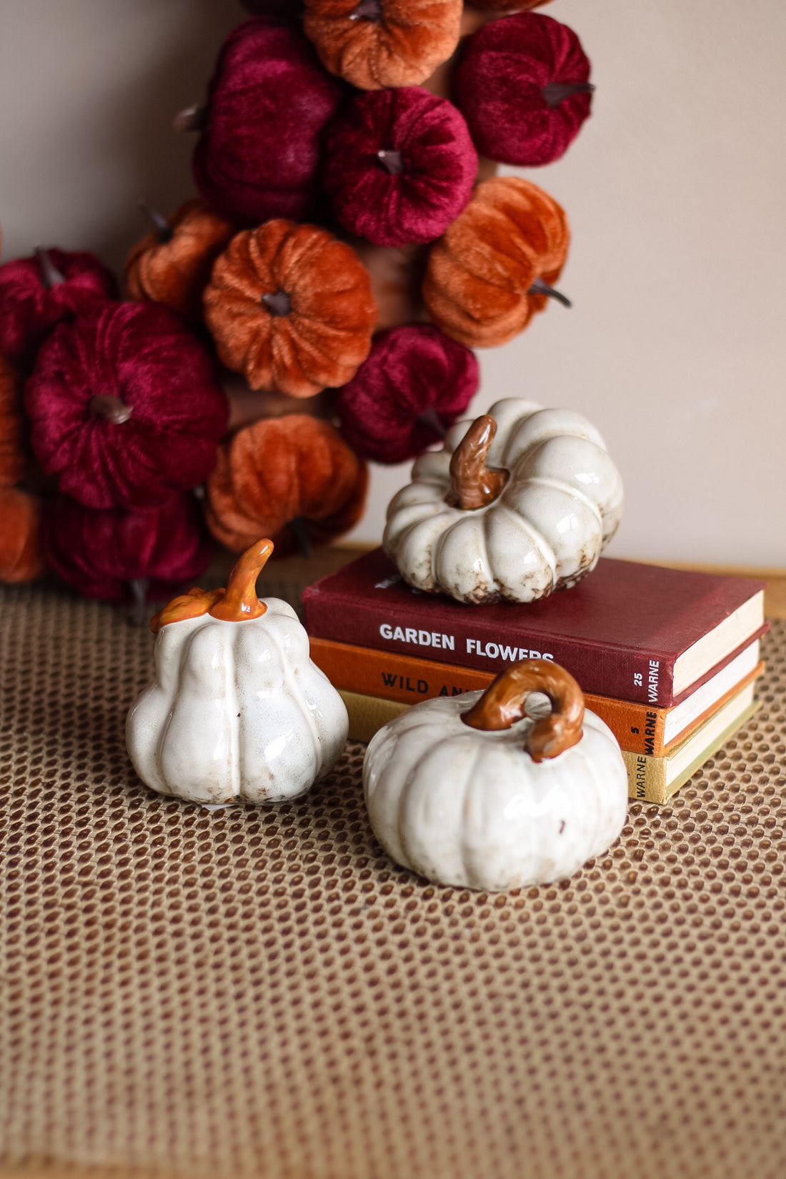 Decorative pumpkins on books with a background of colorful pumpkins.