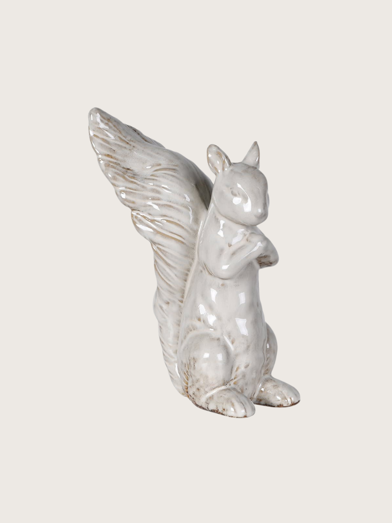 White ceramic squirrel figurine with long bushy tail on a light gray background