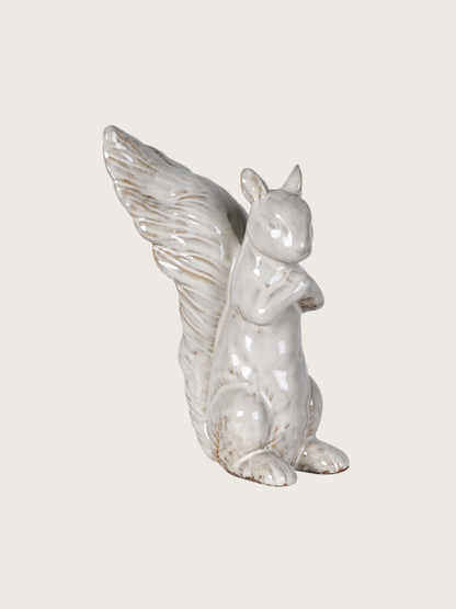 White ceramic squirrel figurine with long bushy tail on a light gray background