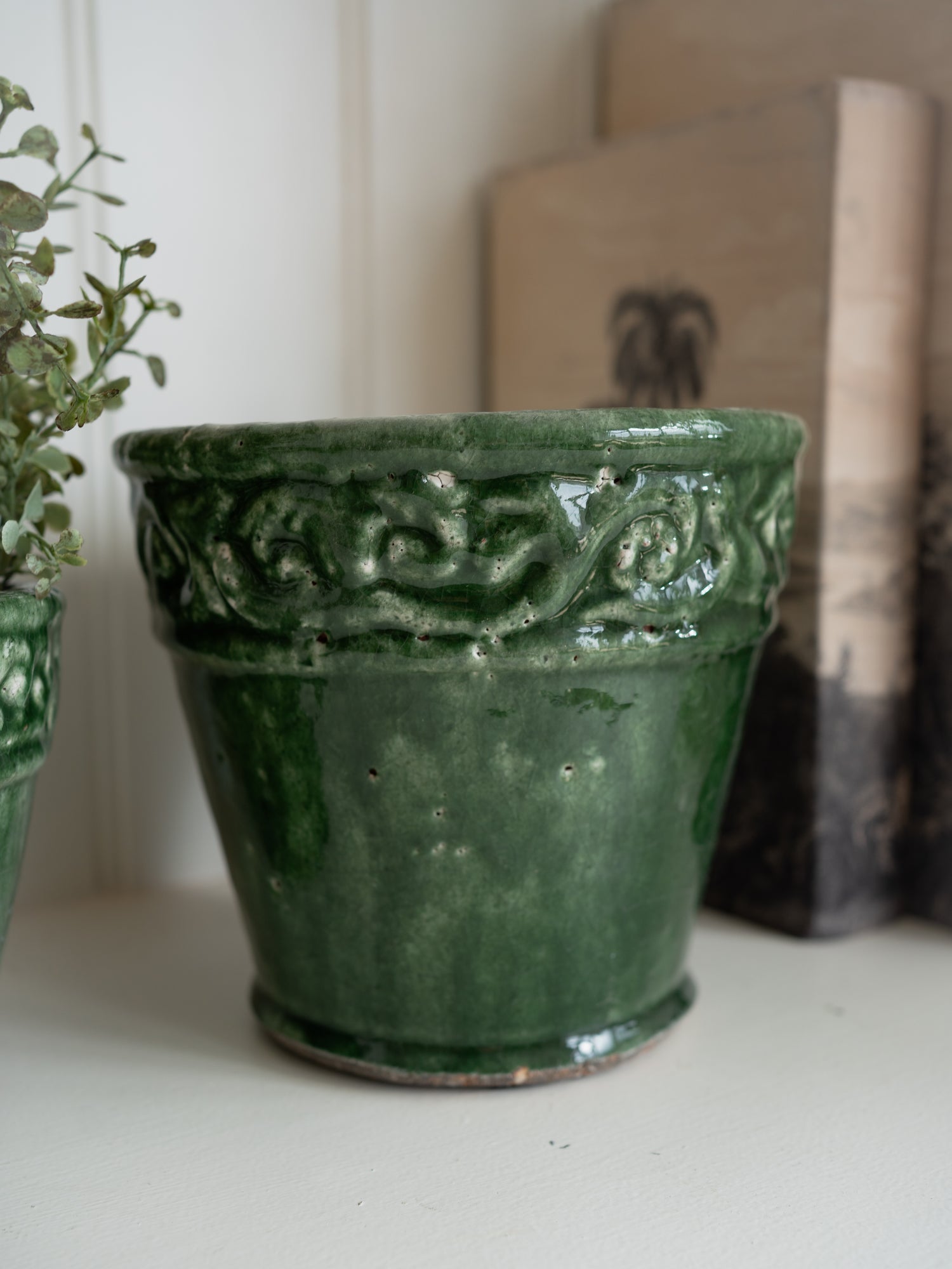 Green ceramic pot with intricate designs on a white surface