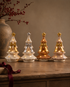 Large Sugar Plum Ceramic Trees on wooden sideboard with vase filled with faux red berries in the background