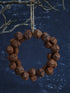Decorative wreath made of brown jingle bells on a dark blue background