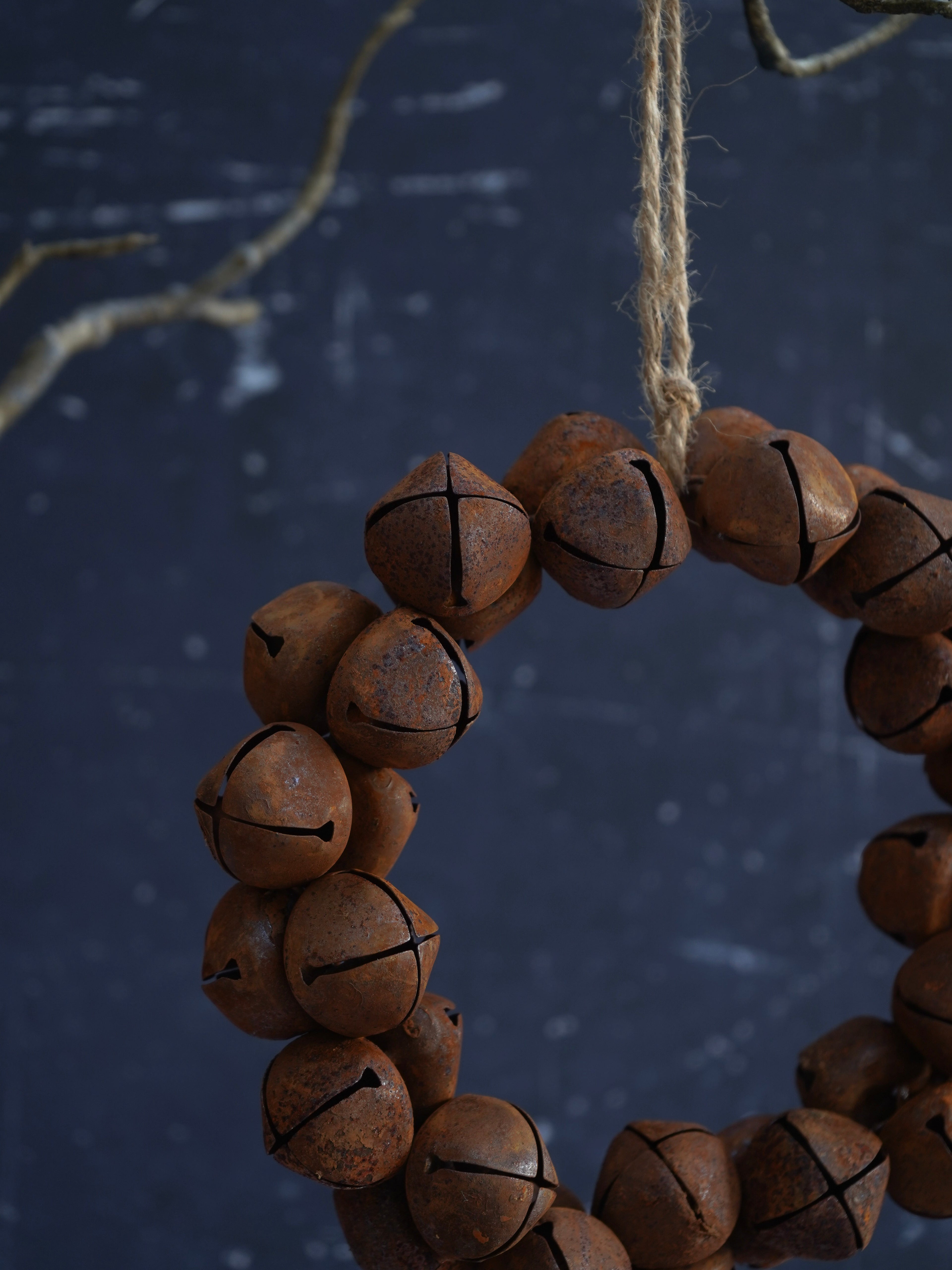 Wooden jingle bell wreath hanging against a dark background
