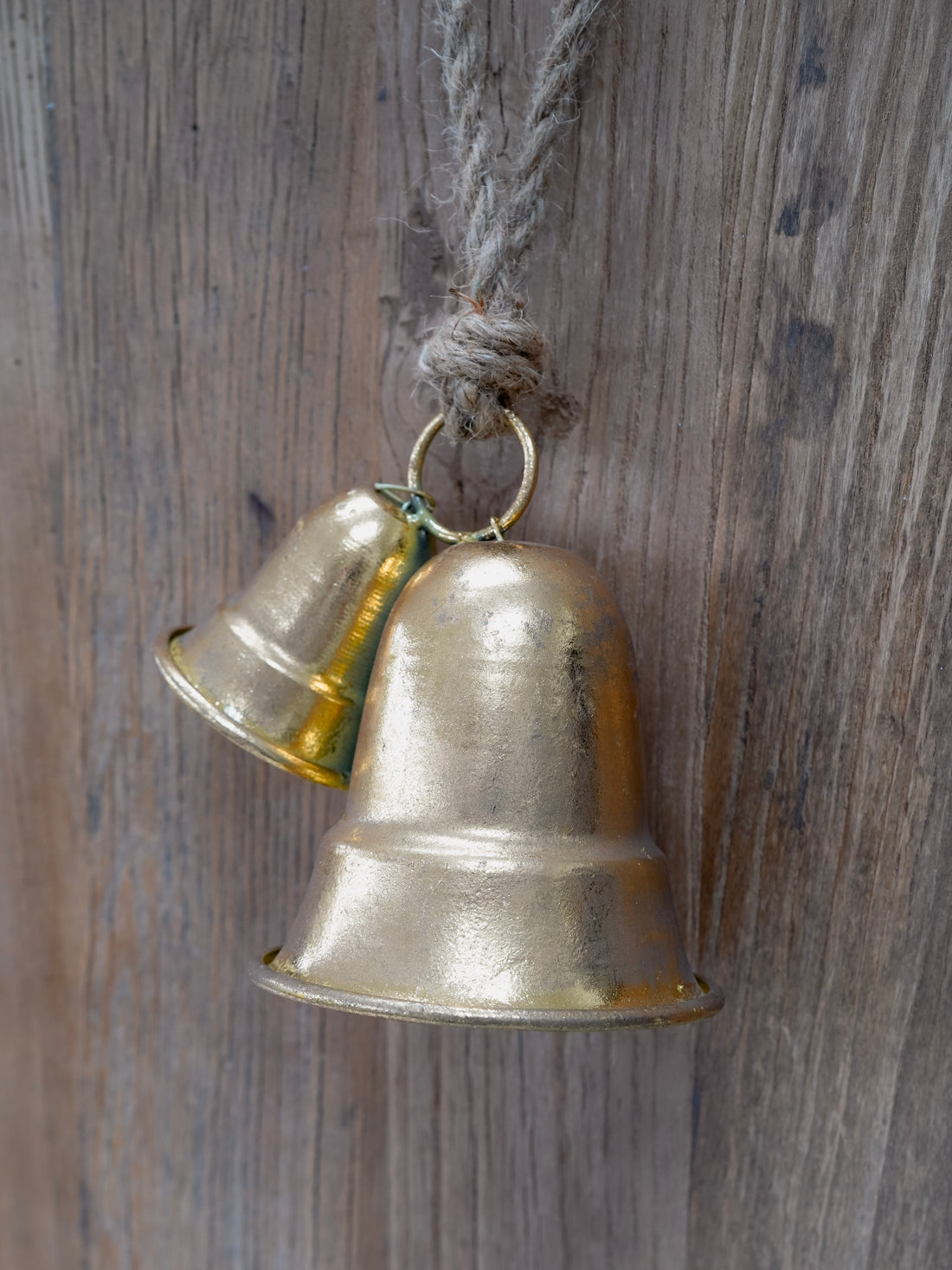 Two brass bells hanging on a wooden surface
