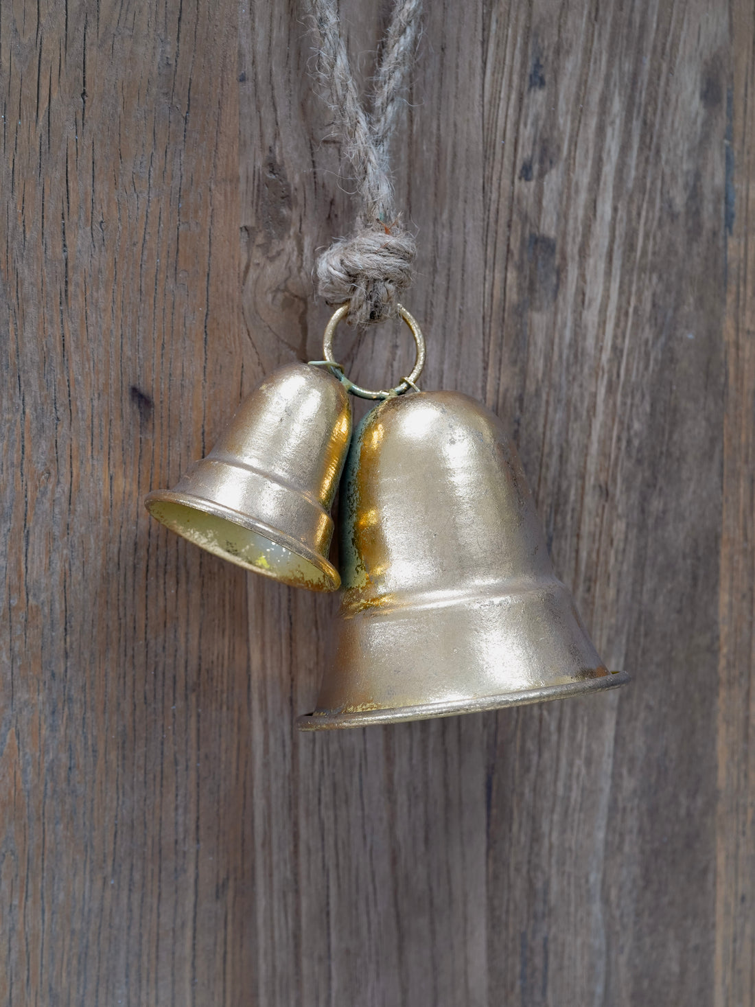 Two brass bells hanging on a wooden surface