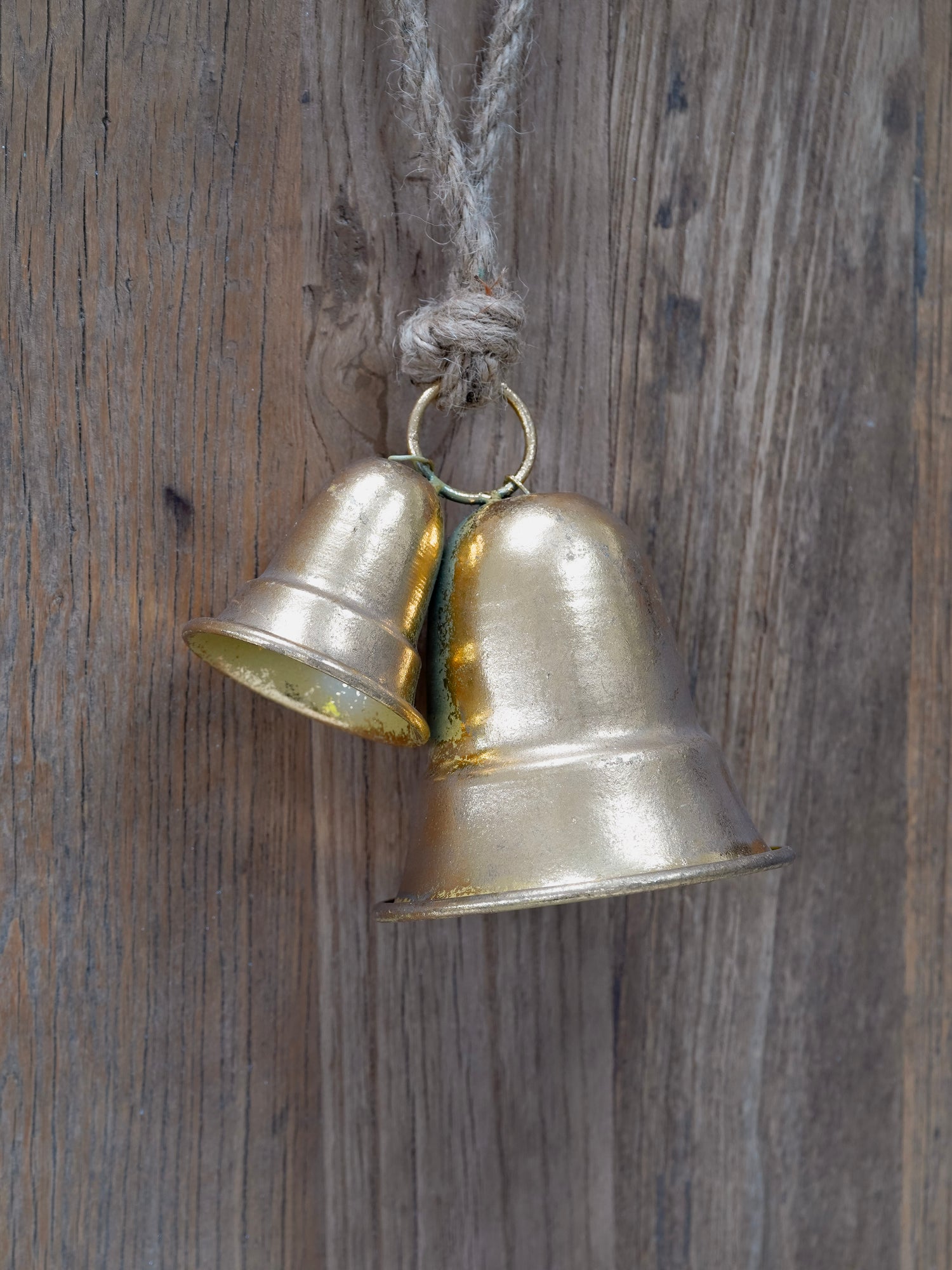 Two brass bells hanging on a wooden surface