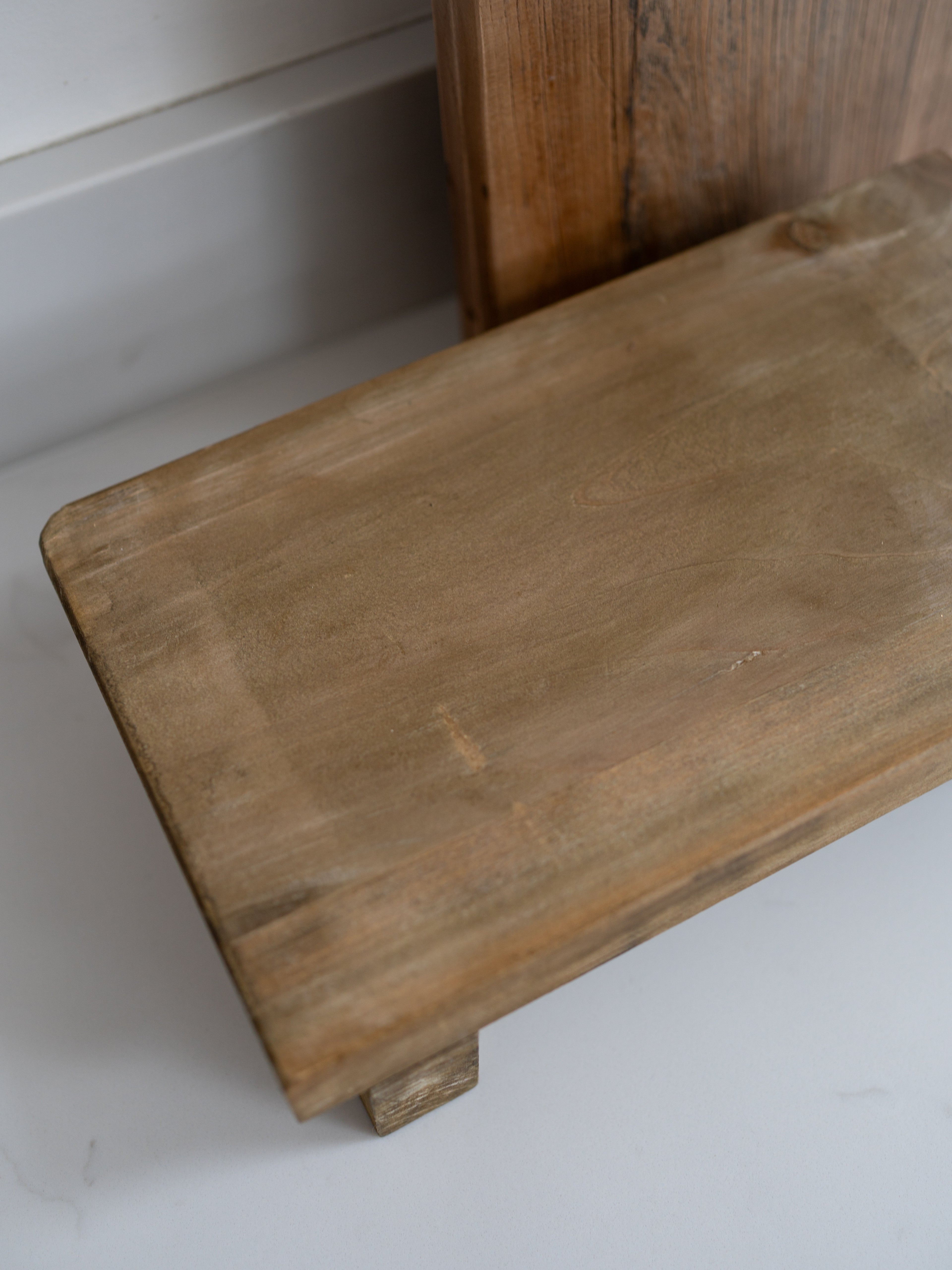 Wooden bench with a worn surface on a white floor