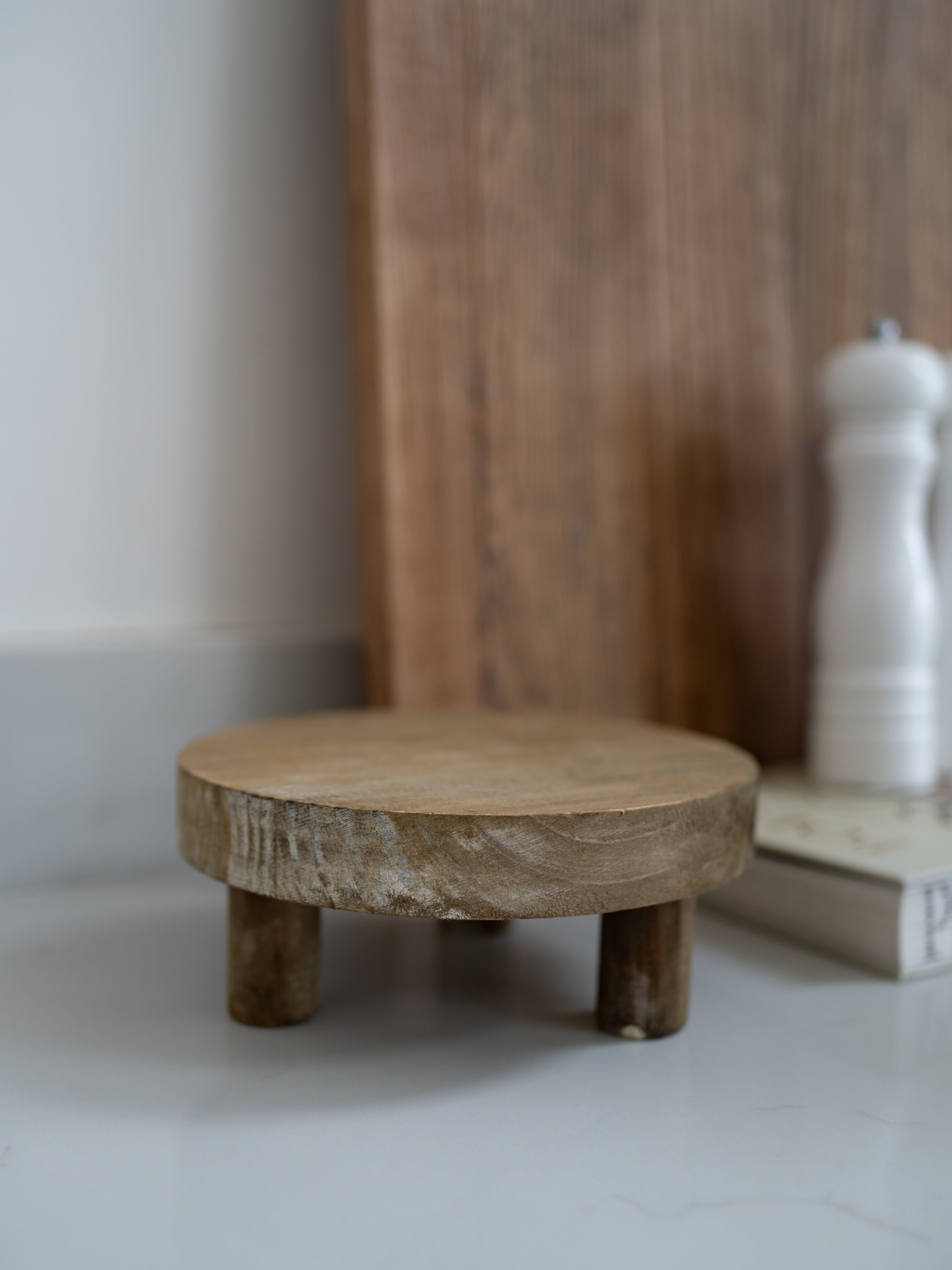 Wooden footstool on a white surface with a blurred background