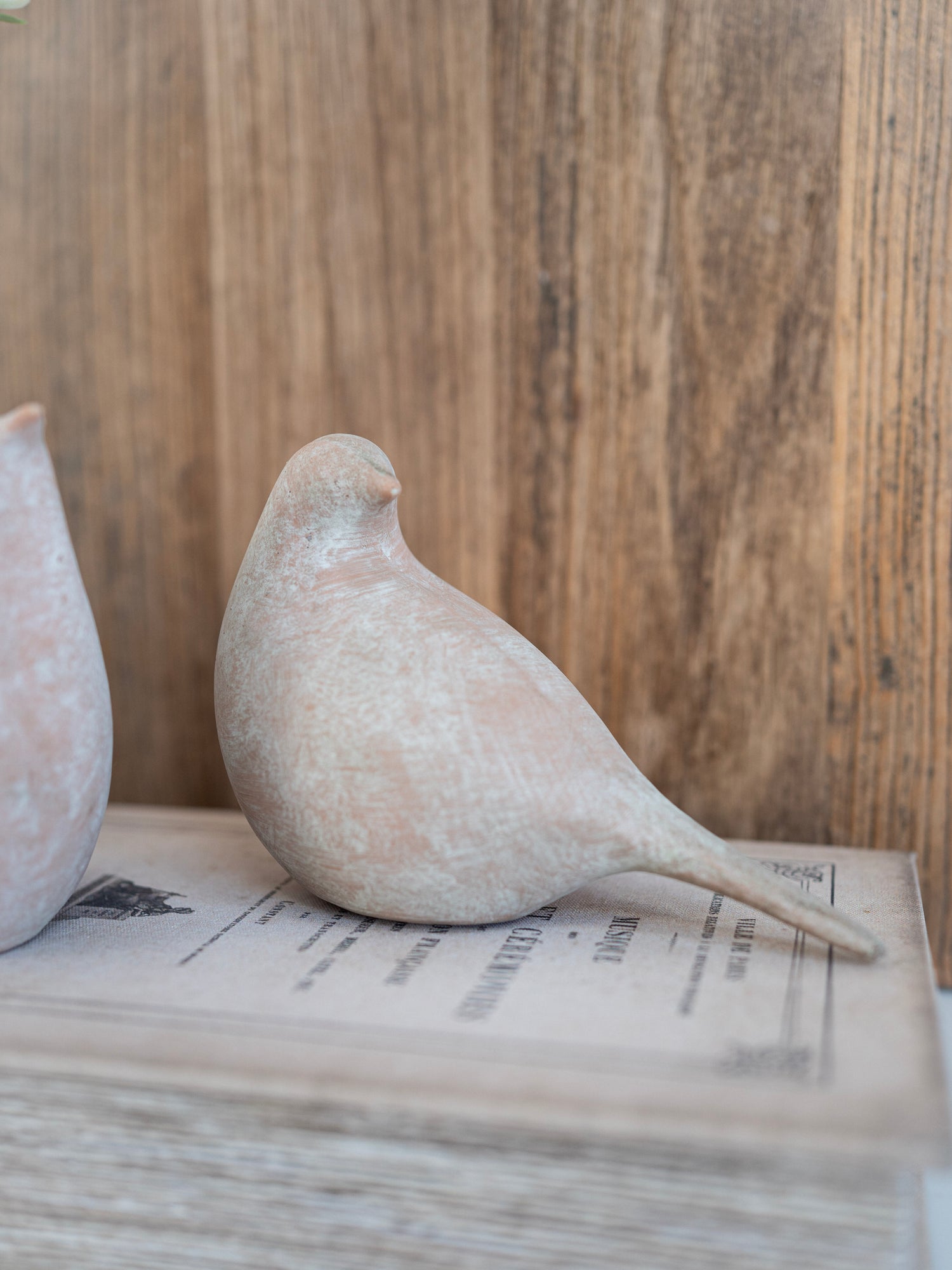 Decorative stone bird on a stack of books with a wooden background