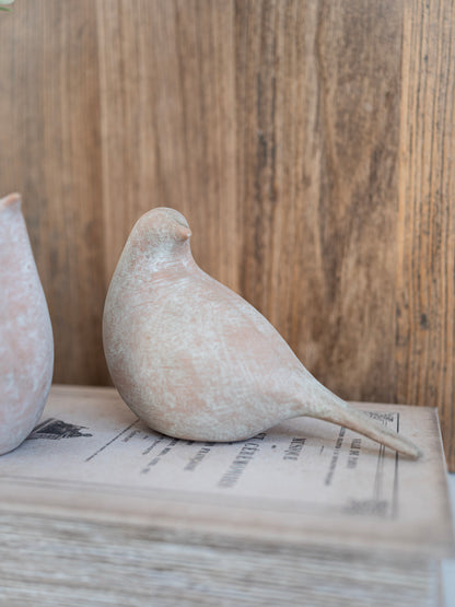 Decorative stone bird on a stack of books with a wooden background