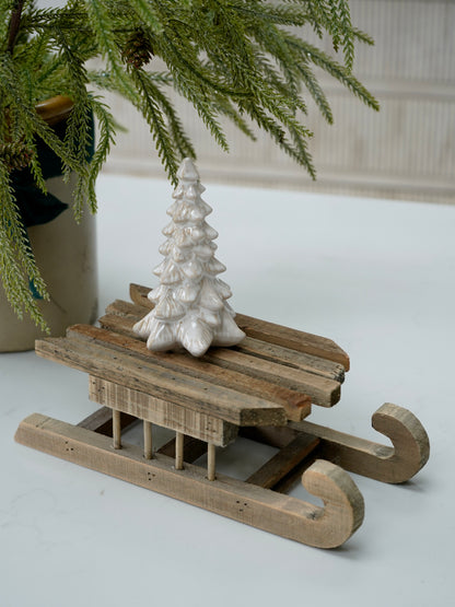 Decorative wooden sled with a white ceramic tree on a light background