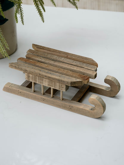 Wooden sled ornament on a white surface with a blurred background