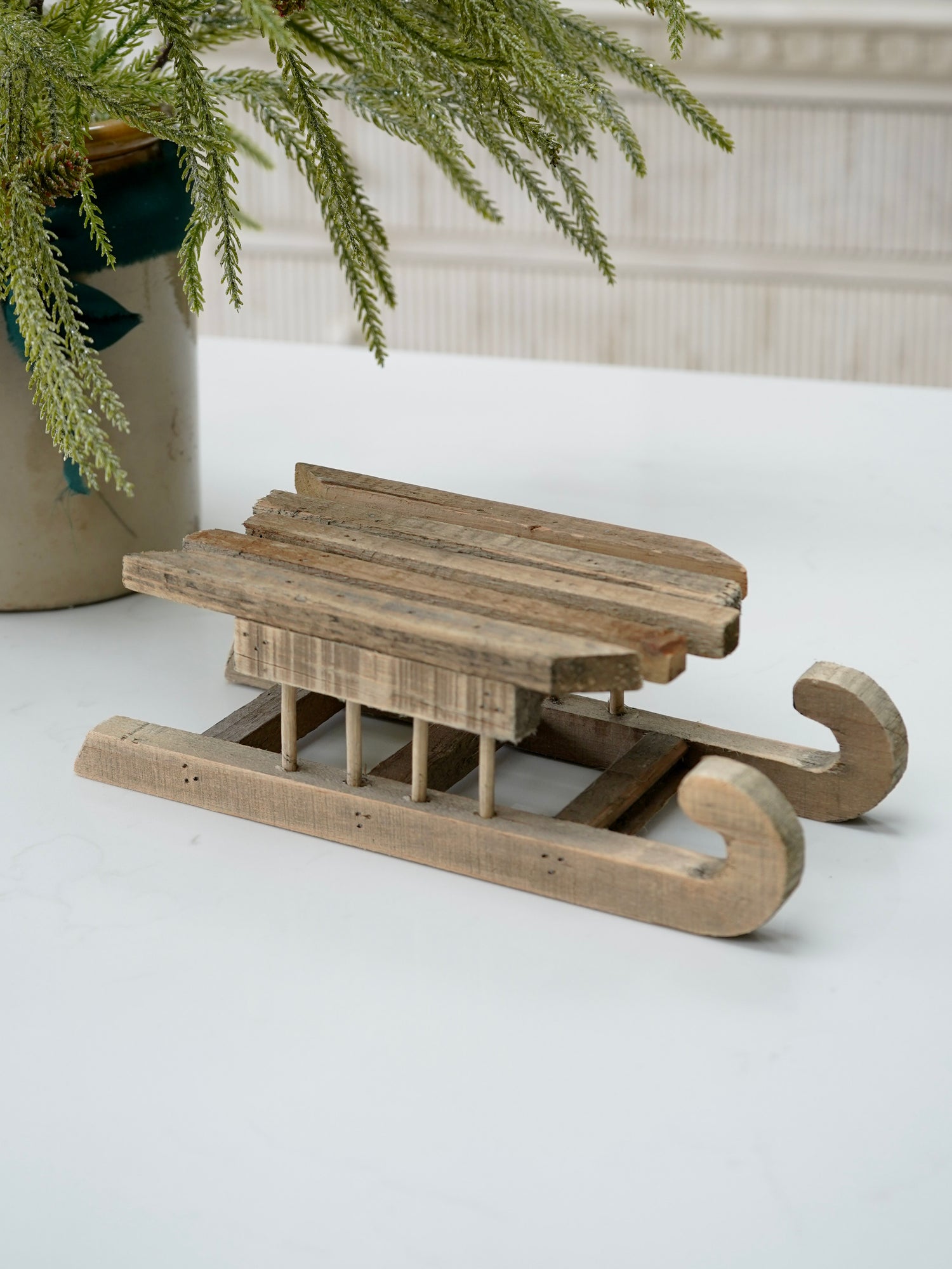 Wooden sled ornament on a white surface with a decorative background