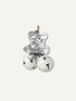 A cluster of two small white christmas bells with black star cutouts, tied together with a silver bow and hanging from a brown string, shown on a plain light background.
