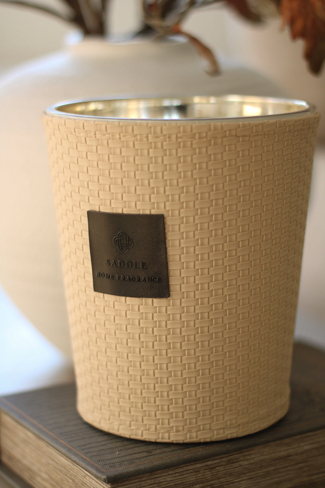 Beige woven candle holder with a label on a wooden surface
