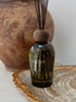 A green salinas diffuser bottle with dark wooden top on a decorative surface