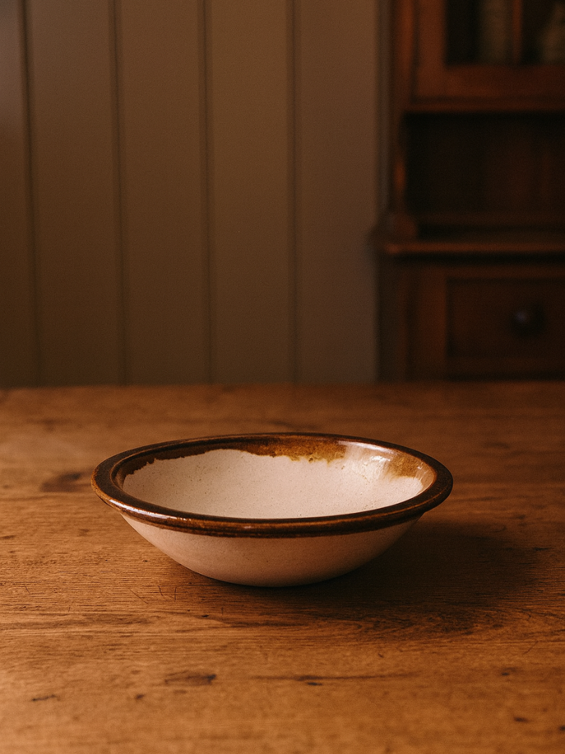 White terracotta bowl with brown rim on a wooden surface