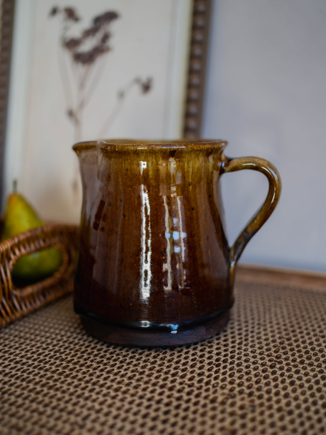 Brown ceramic salt glazed jug on a textured surface with a blurred background