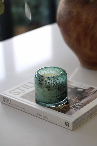 Teal glass candle on a book with a blurred background