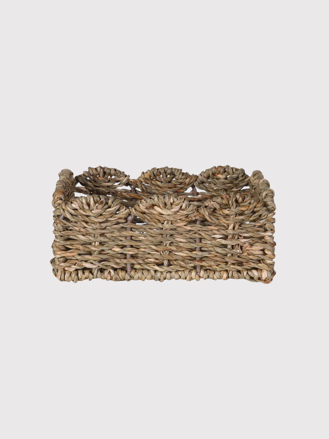 Woven seagrass napkin holder basket with floral patterns on a light gray background