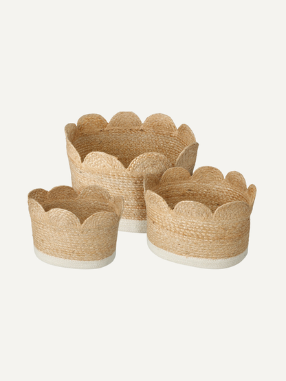Set of three woven seagrass storage baskets with scalloped edges on a white background