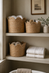 Seagrass scalloped storage baskets and folded towels on a shelf in a bathroom setting.