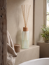 Diffuser with reeds on a windowsill in a bathroom setting