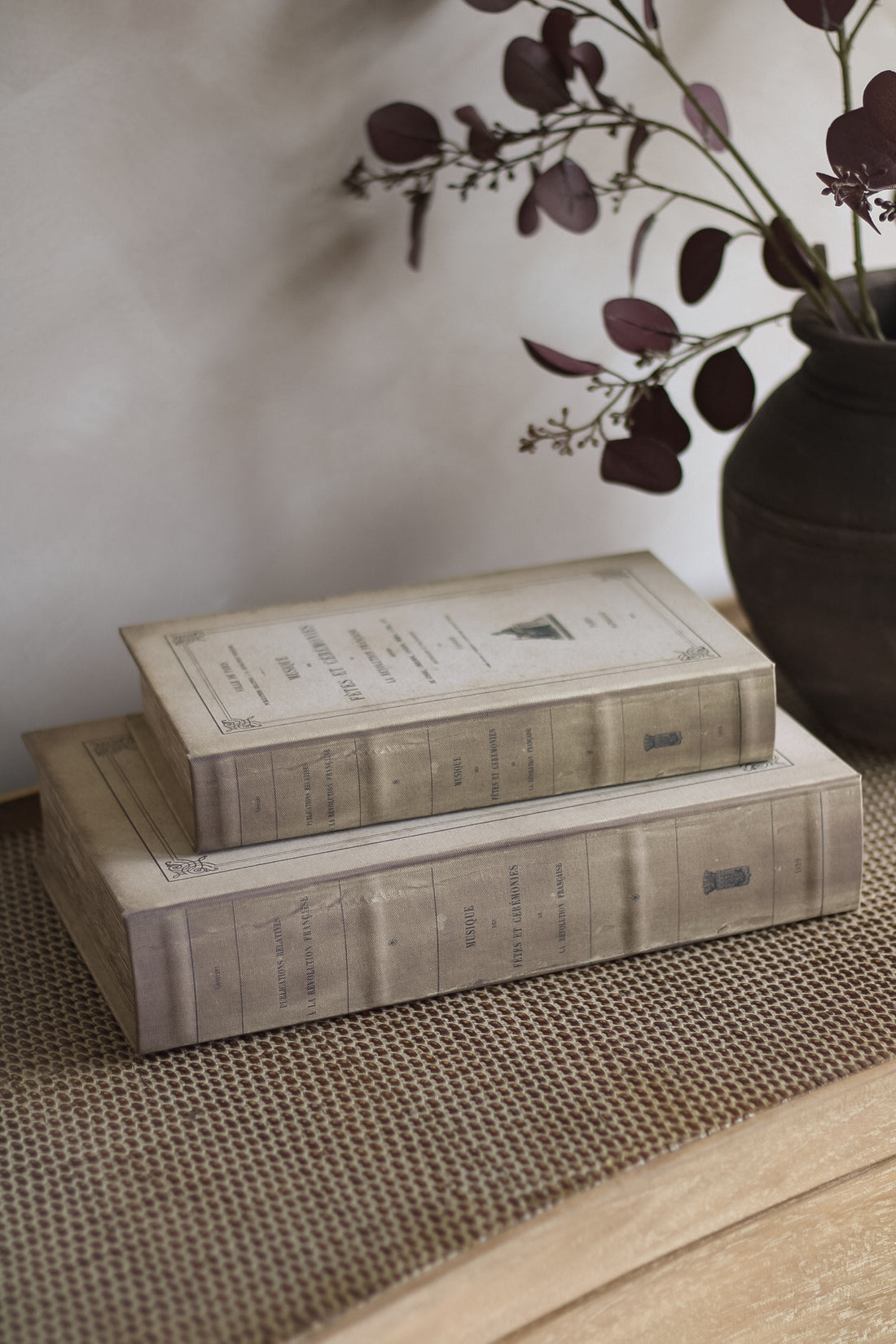 Stack of decorative books with a vase of flowers on a textured surface