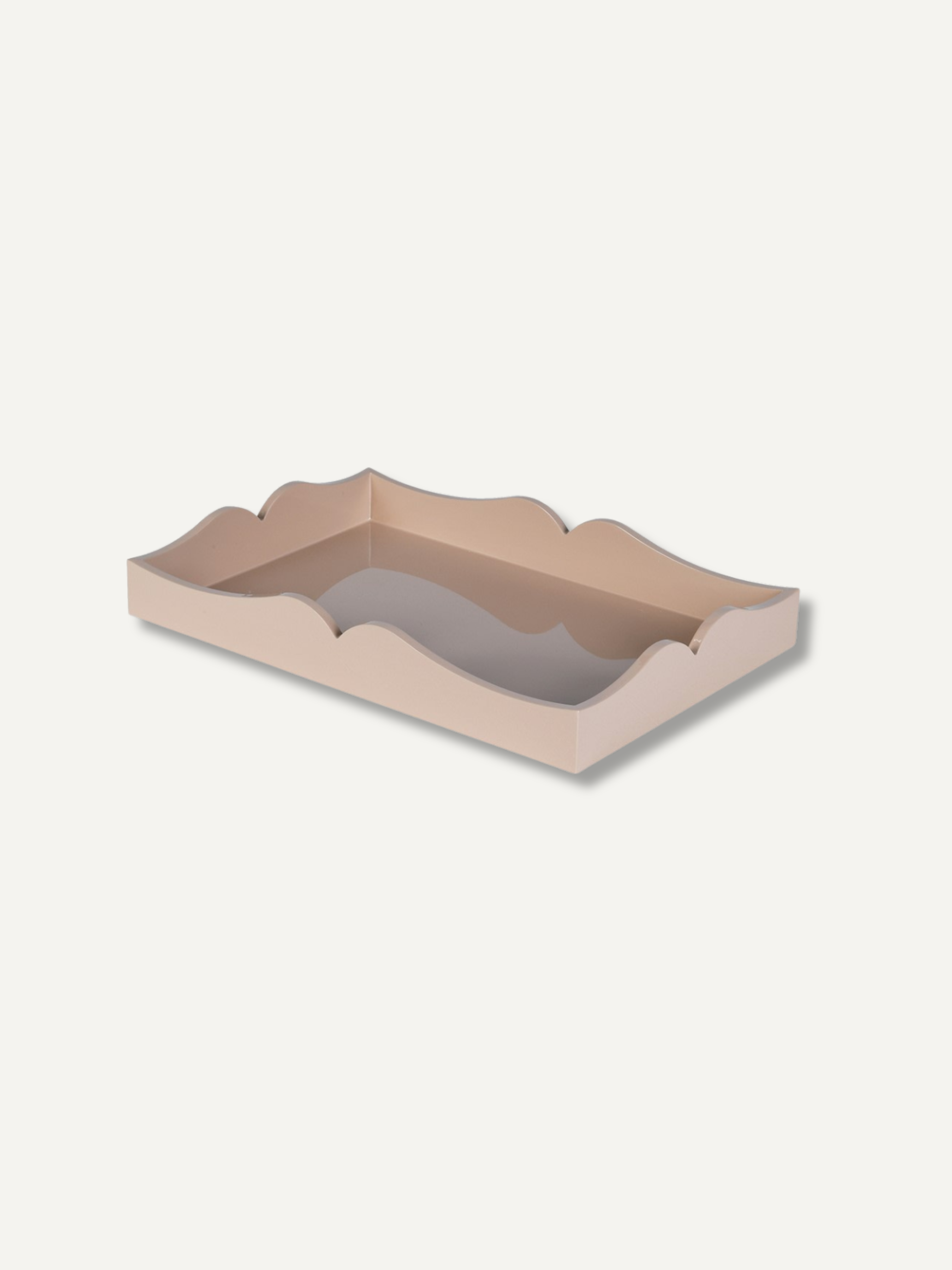 A rectangular tray with scalloped edges in a light beige or blush pink color, shown from an elevated perspective on a solid off-white background.