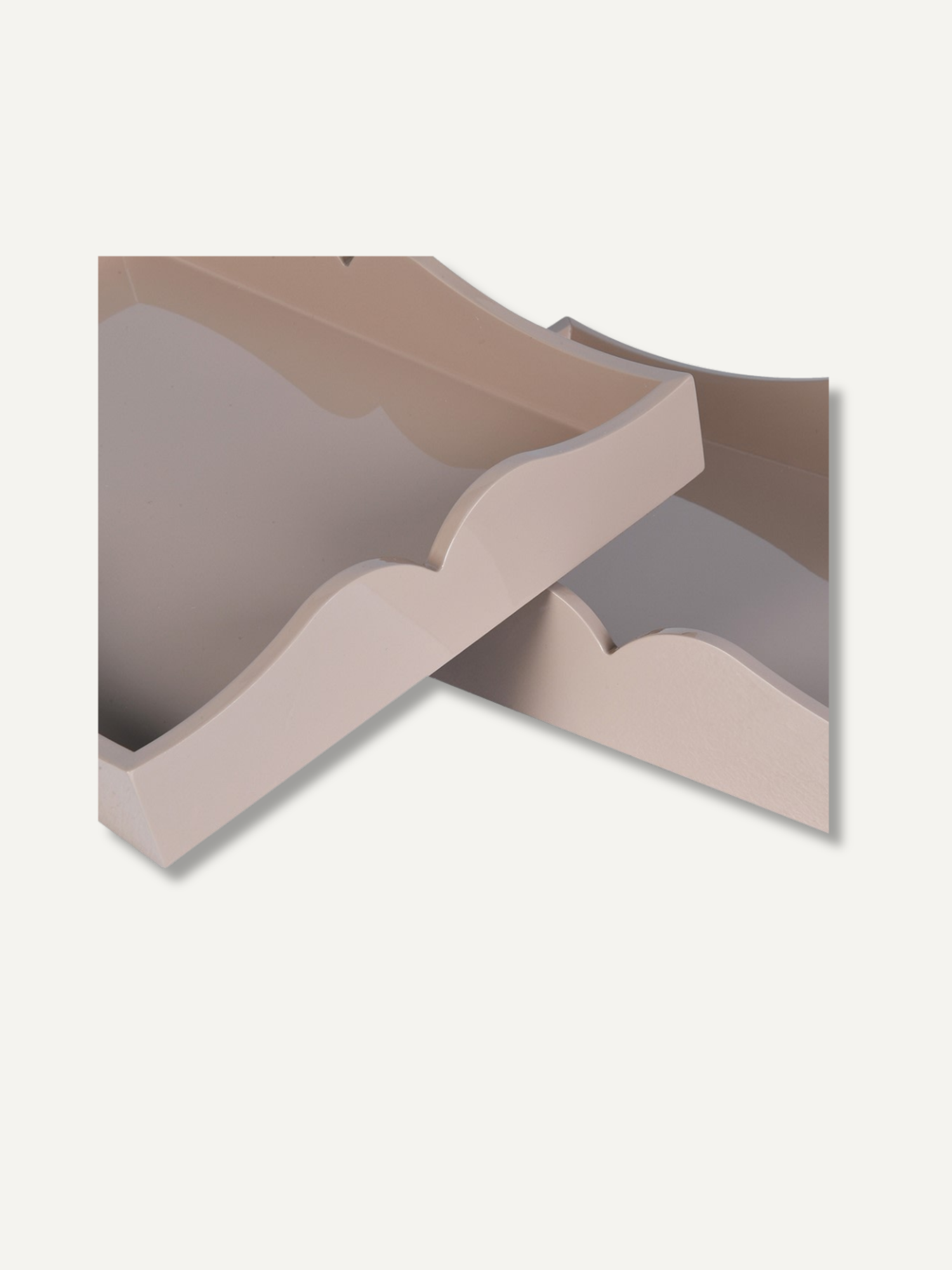 Two overlapping decorative trays in a light beige or blush-taupe color, shown on a plain off-white background.