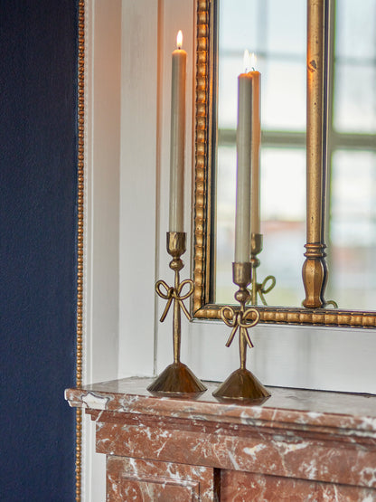 Set of 2 Sculpted Brass Bow Candlesticks, on red marble mantlepiece with antique gold framed mirror