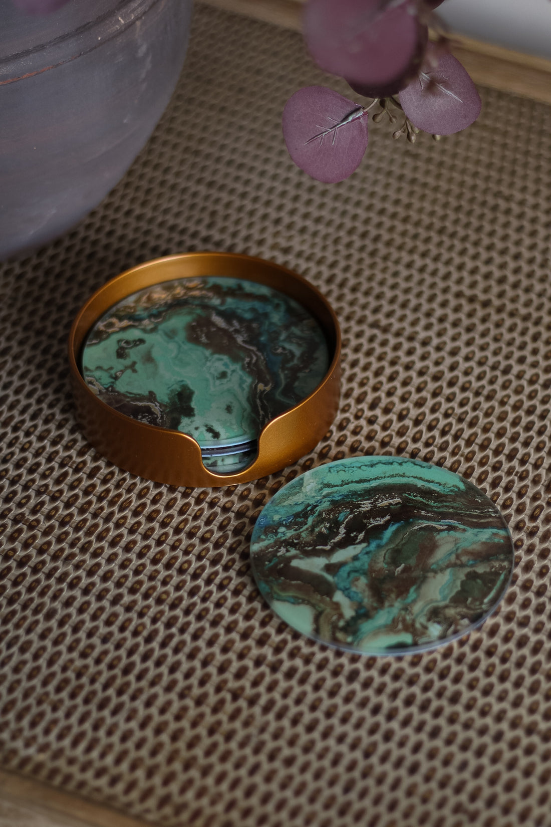 Turquoise stone with gold container on a textured surface