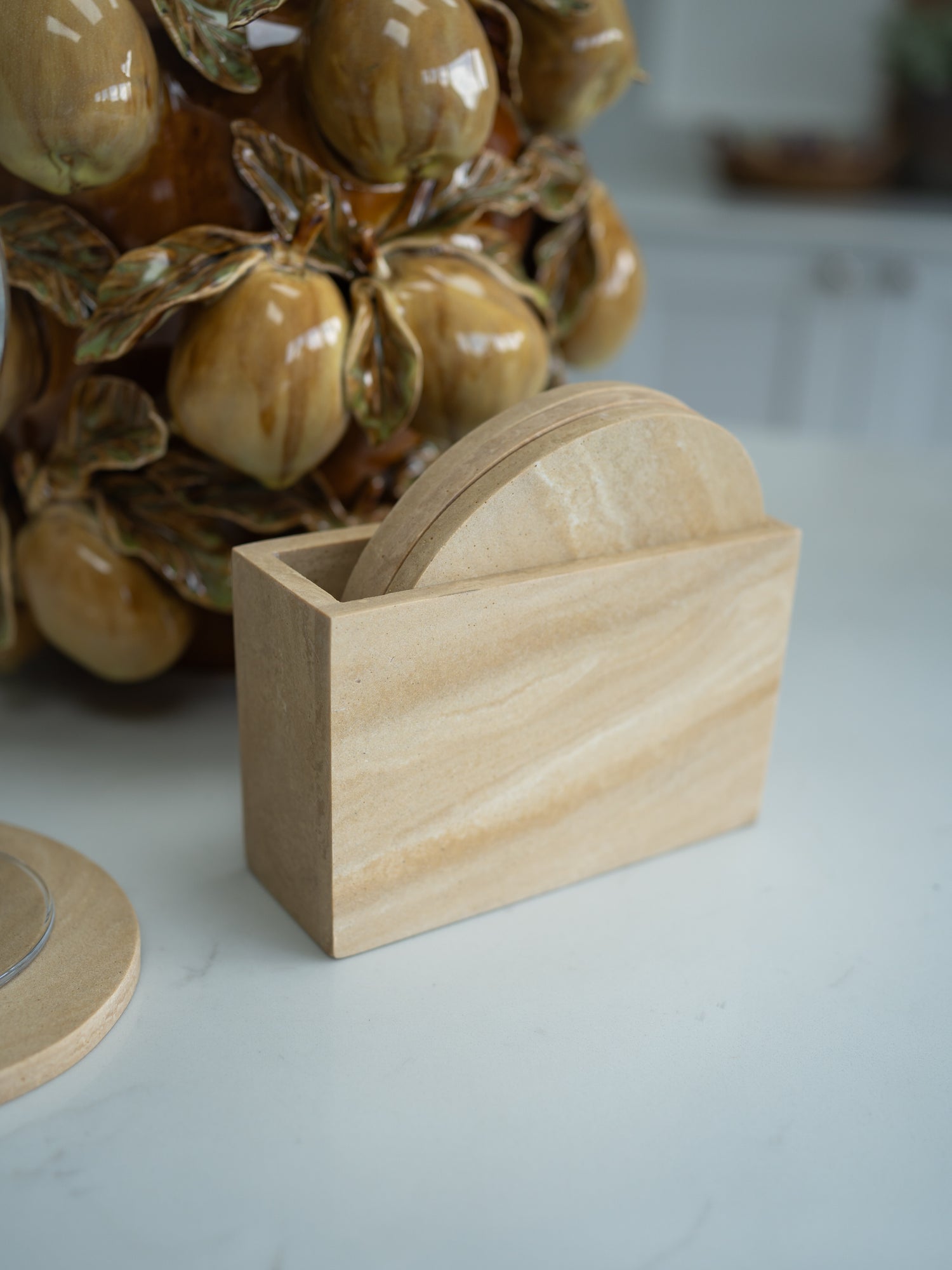 Travertine coaster holder with coasters on a light surface