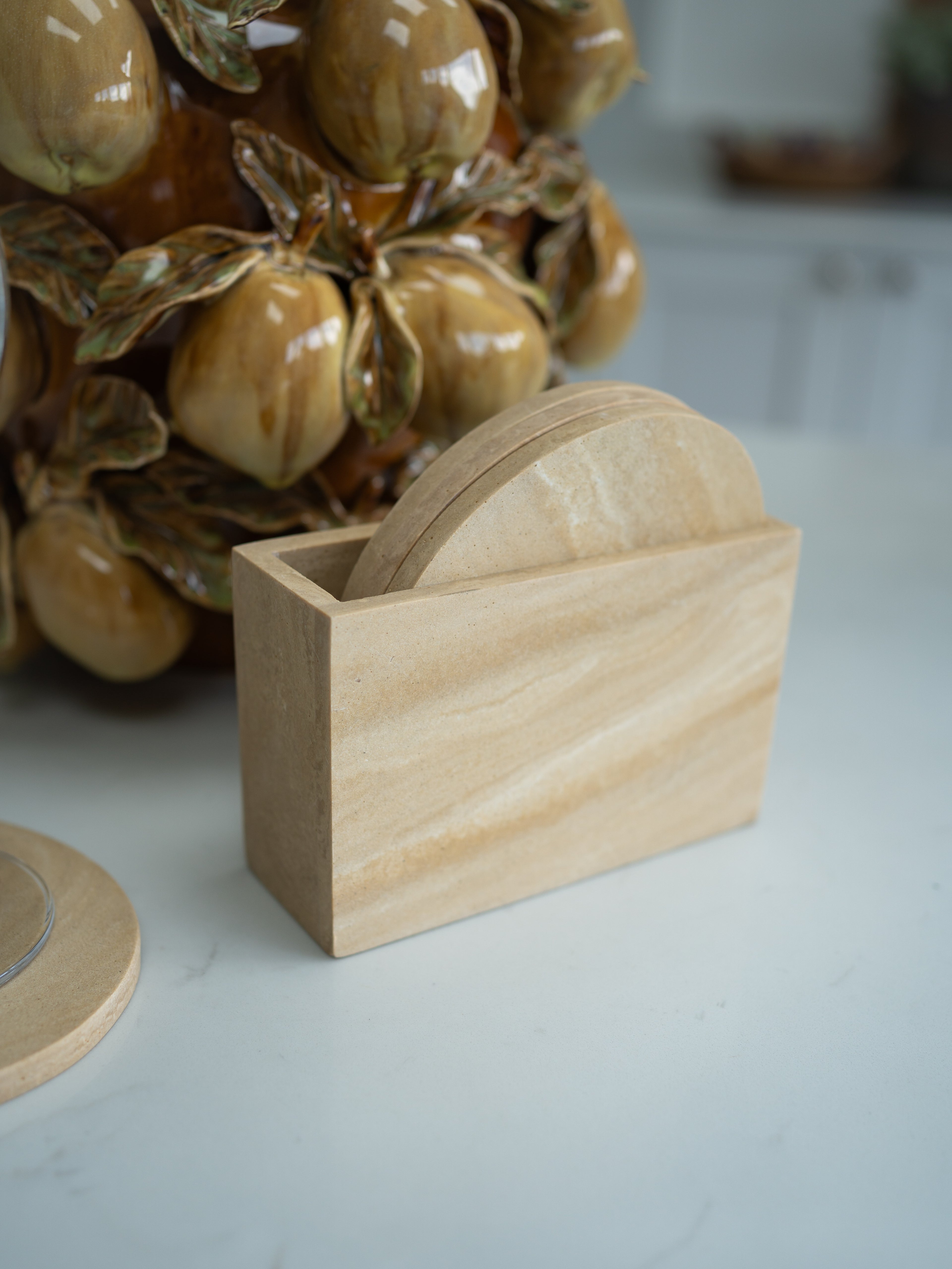 Travertine coaster holder with coasters on a light surface