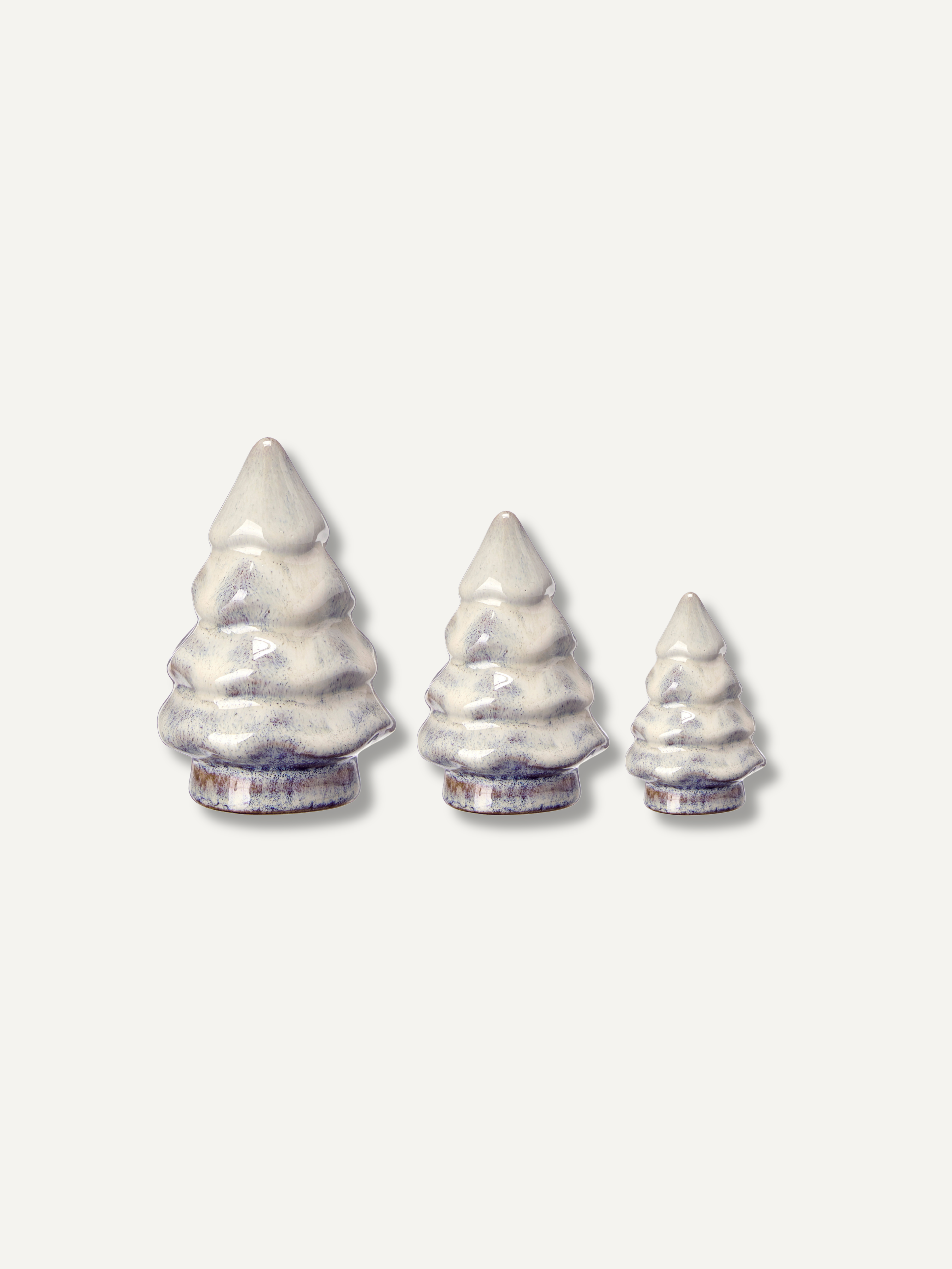 Three small christmas tree-shaped ceramic objects in graduated sizes, arranged from left to right on a plain light background.
