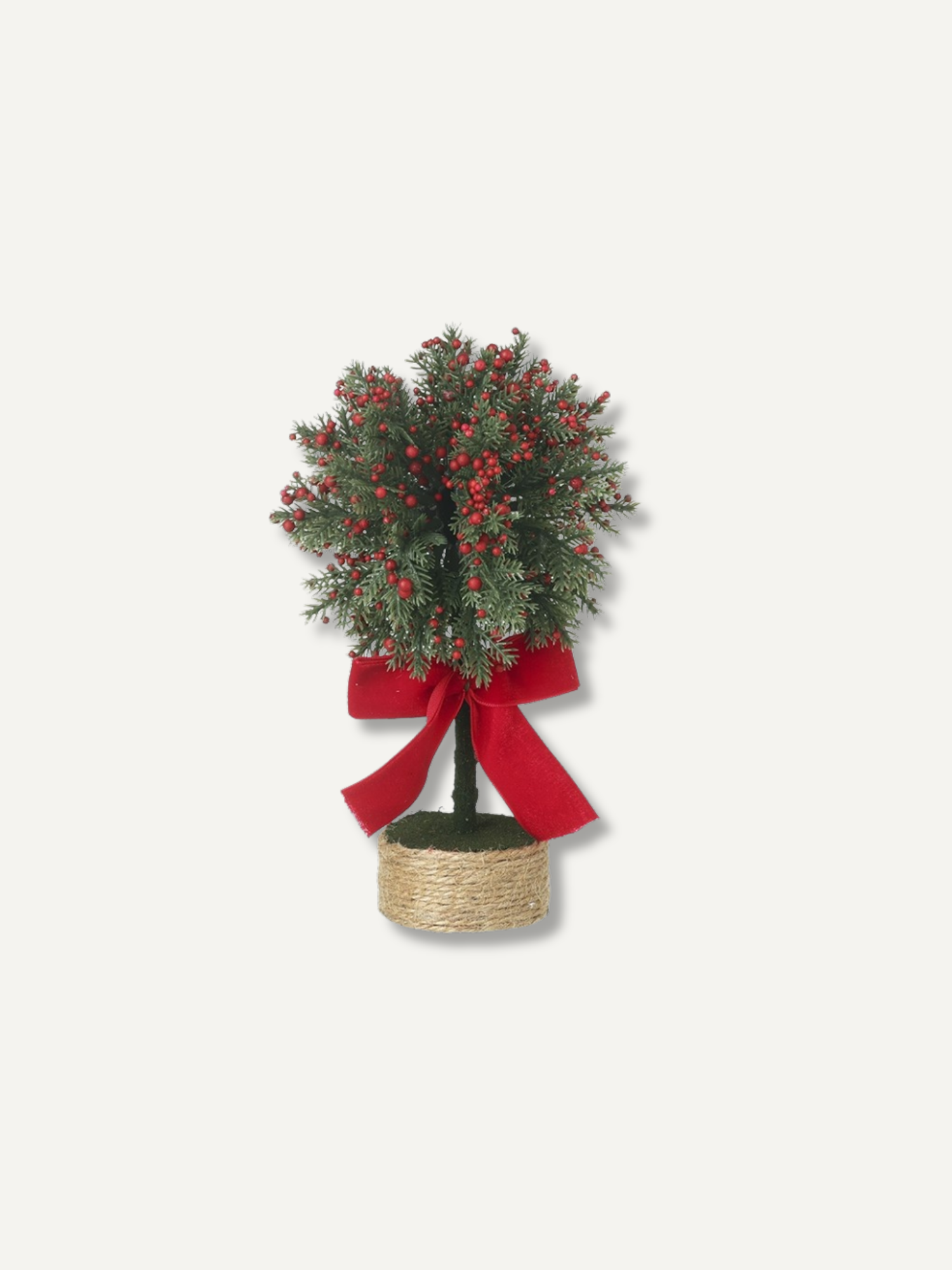 A small artificial Christmas tree with green needles, red berries, and a large red ribbon bow, potted in a woven basket on a light gray background.