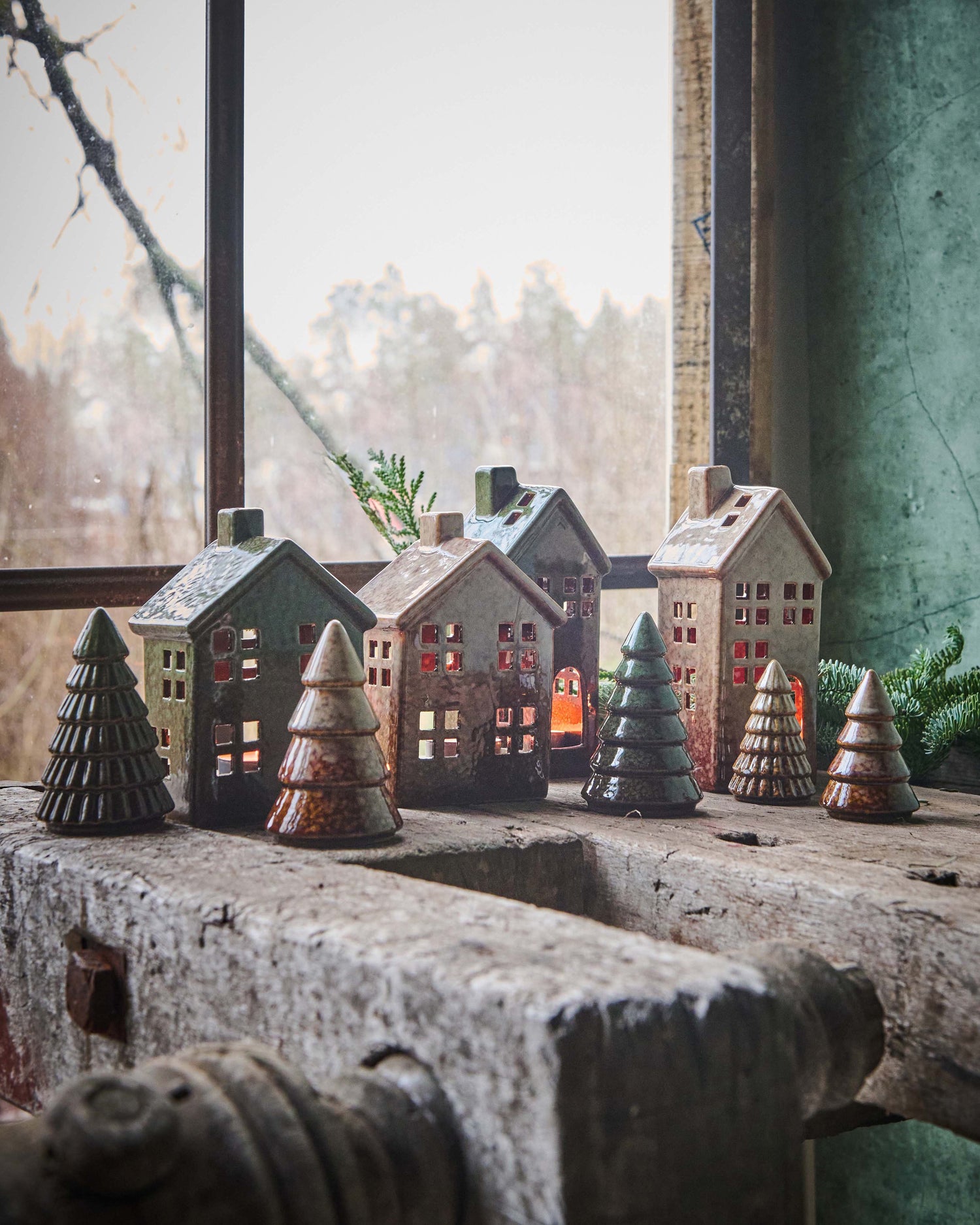 collection of reactive glazed trees and houses on rustic wooden bench