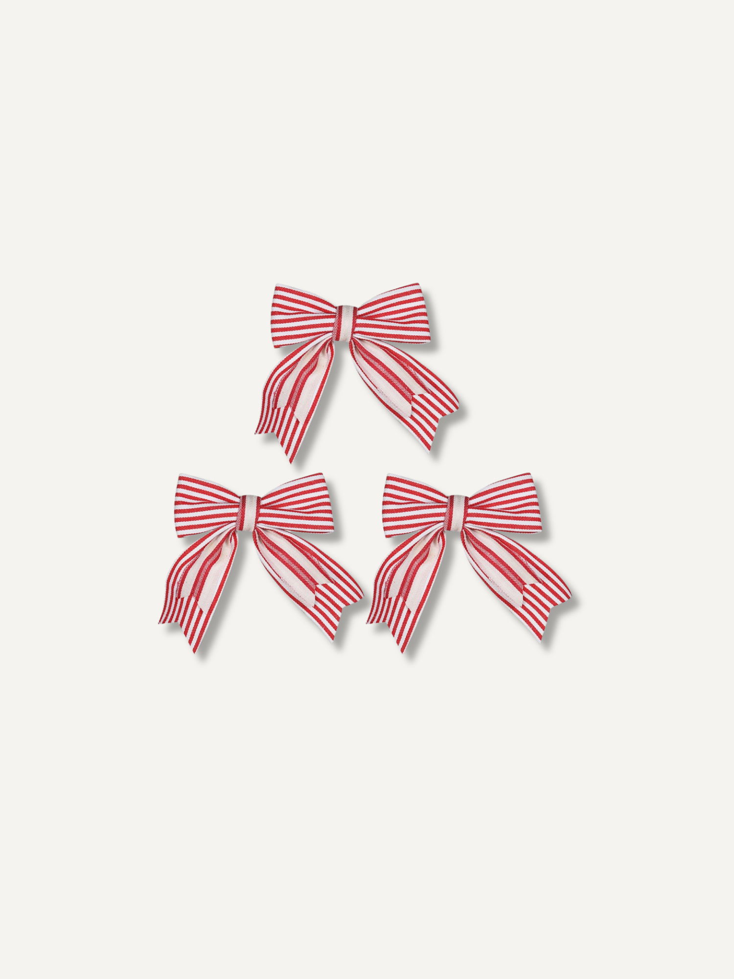 Three red and white striped fabric christmas bows arranged in a pyramid on a light beige background.